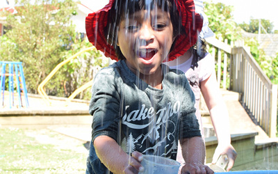 boy catching cascading water at daycare