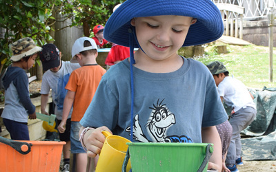 boy in hat with bucket and cup at childcare