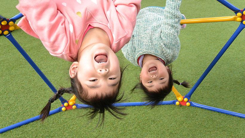 girls hanging upside down from bars at daycare