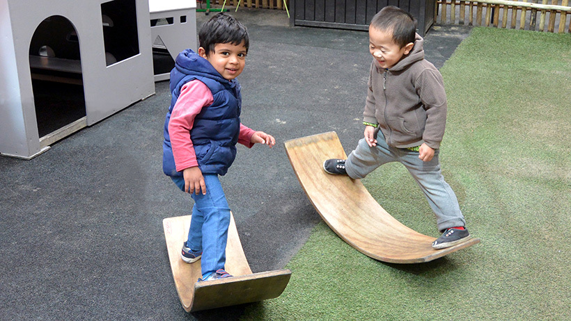 boys balancing on curved wood at daycare