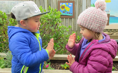 children playing hand clapping game at preschool