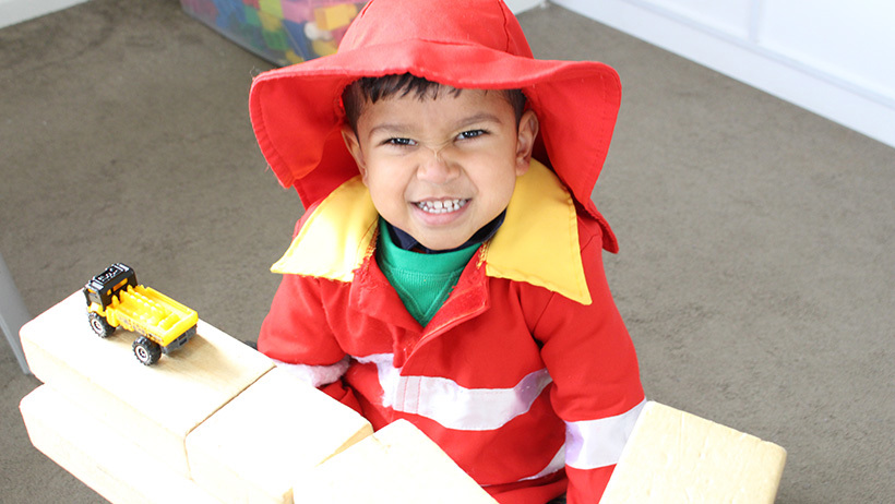 boy smiling with truck and blocks at preschool