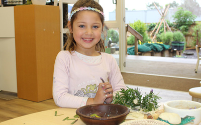 girl playing with plant mixture at daycare