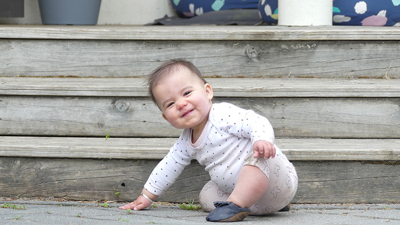 baby girl smiling crawling down steps at daycare